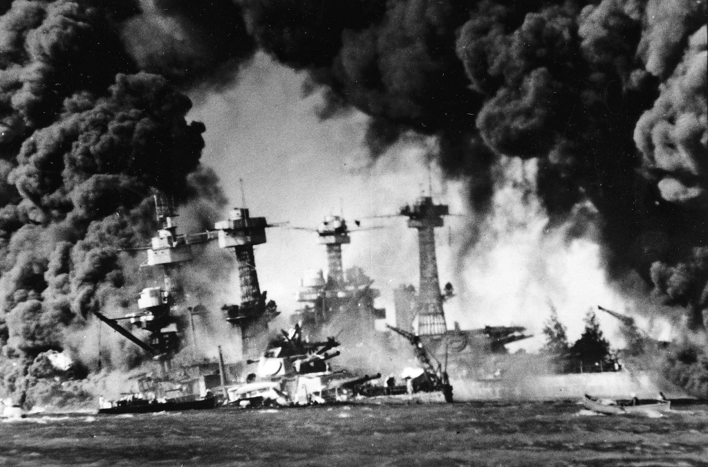 Fogo e nuvens de fumaça cobrem os navios americanos após o bombardeio japonês em Pearl Harbor, 1941.